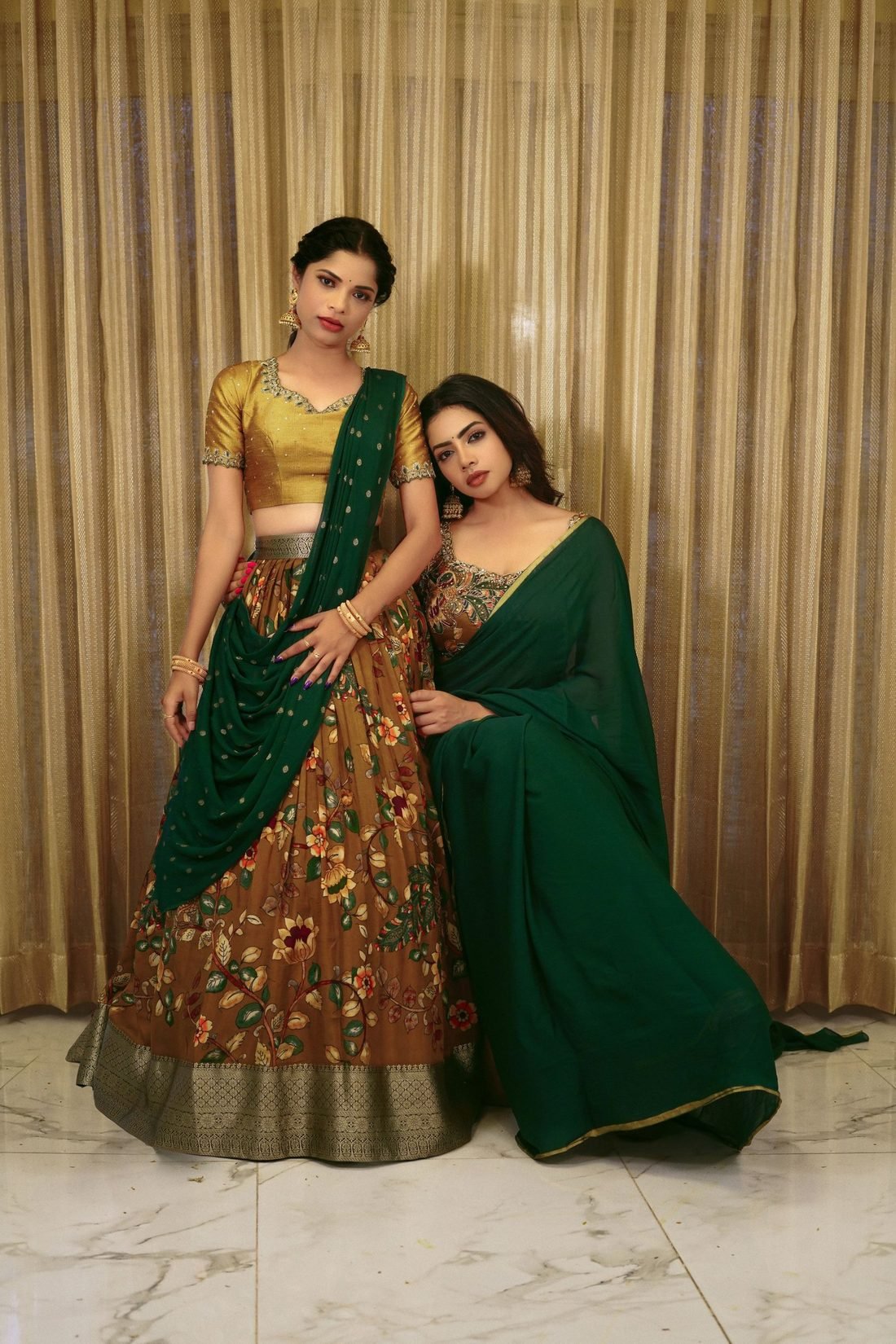 Two women in a green saree and a floral lehenga with a green dupatta
